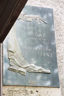 Pamětní deska Rudolfu Durčákovi, řídícímu učiteli umučenému v&nbsp;Osvětimi, na budově bývalé základní školy na ul. Těšínská v&nbsp;Radvanicích (dnes sídlo UNIMETRA, s.r.o.,&nbsp;hlavní budova), 2007. Zdroj: Archiv města Ostravy, Sbírka...